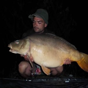 Man holding carp at night